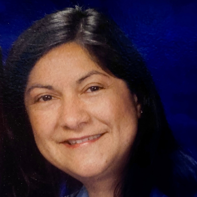 A headshot of Maria Cano on a blue background